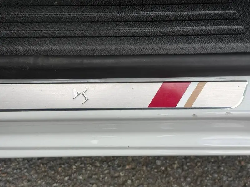 Gros plan sur la plaque de seuil de porte DS3 Crossback blanc perle avec logo DS et bandes rouges et beiges.