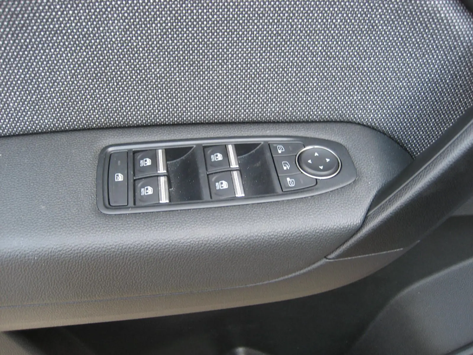 Panneau de commandes des vitres et rétroviseurs côté conducteur de la Renault Symbioz gris Rafale, vue rapprochée intérieure.