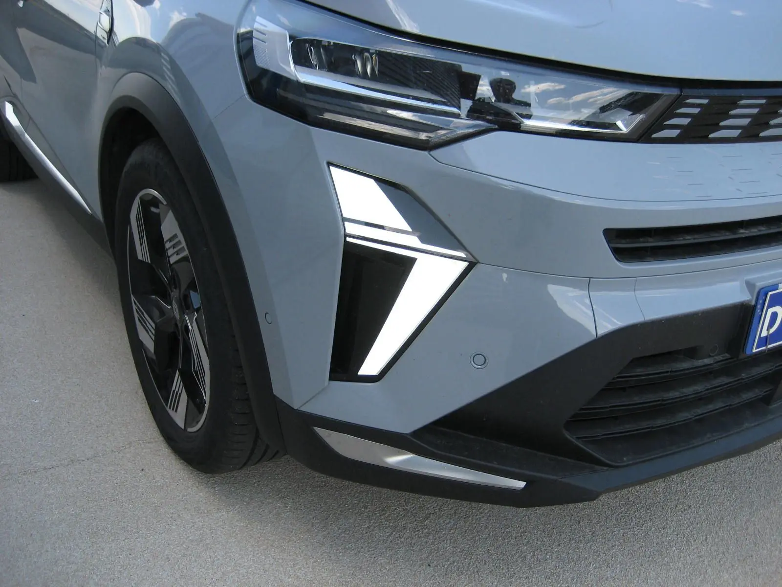 Vue avant droite du Renault Symbioz gris Rafale, mettant en valeur le phare LED et la calandre moderne.