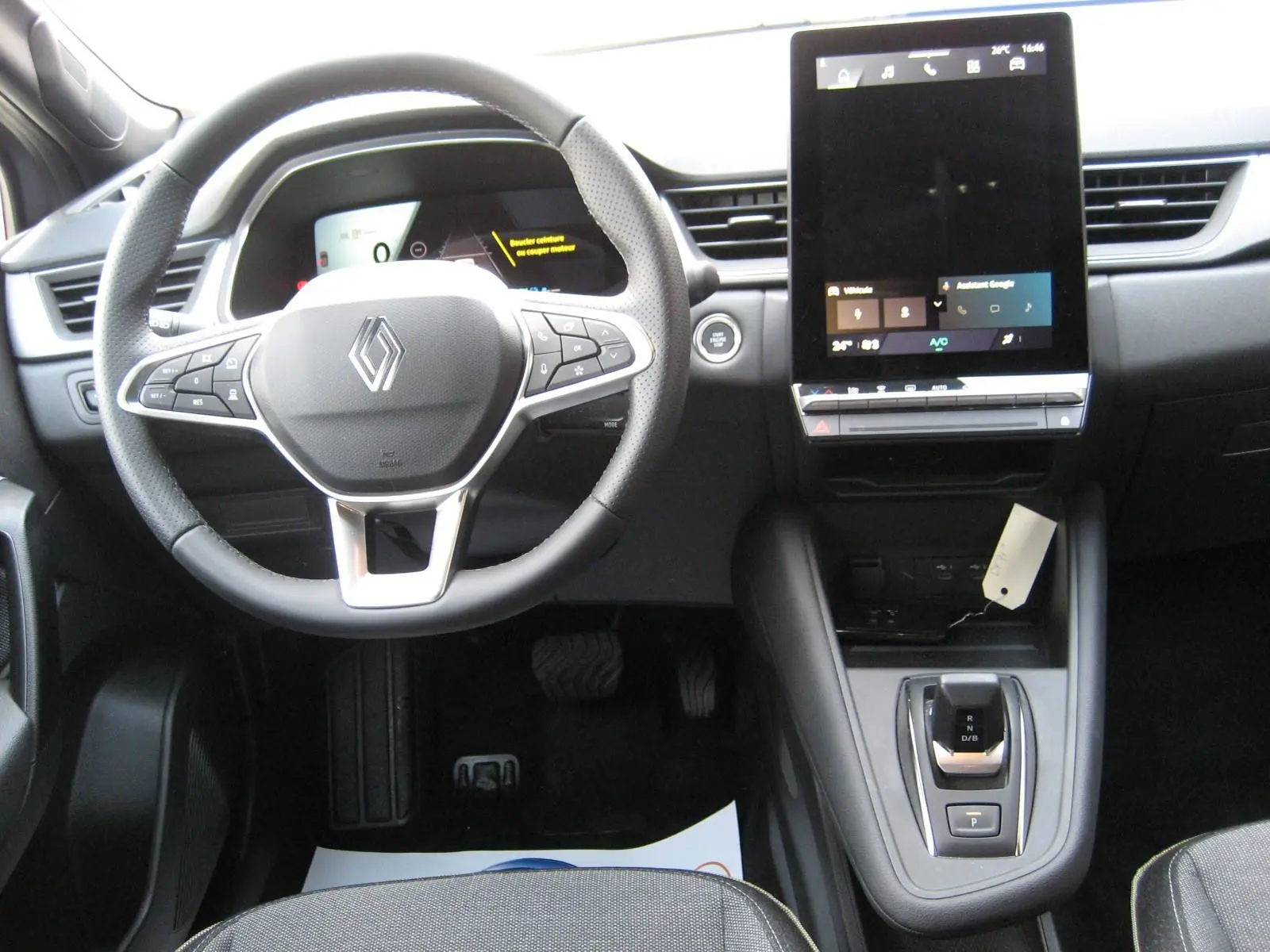 Vue intérieure frontale du tableau de bord gris du Renault Symbioz 2025 avec volant multifonction et écran tactile vertical.