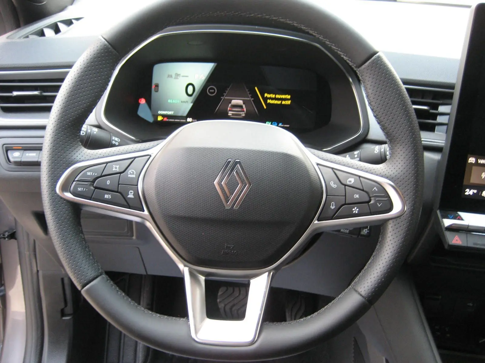 Vue rapprochée du volant noir perforé et du tableau de bord numérique du Renault Symbioz gris Rafale, version hybride 2025.