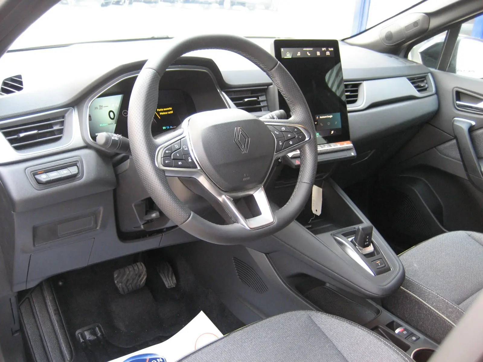 Vue intérieure du poste de conduite du Renault Symbioz gris Rafale, avec volant multifonction et écran tactile vertical.