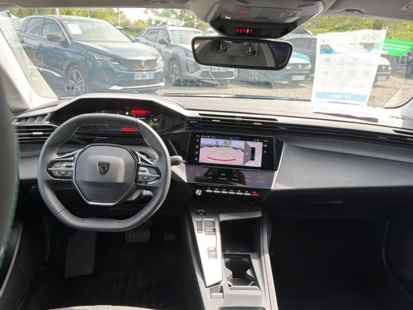 Vue intérieure avant de la Peugeot 408 Hybrid 136 allure 2024, tableau de bord noir avec écran tactile et volant cuir.