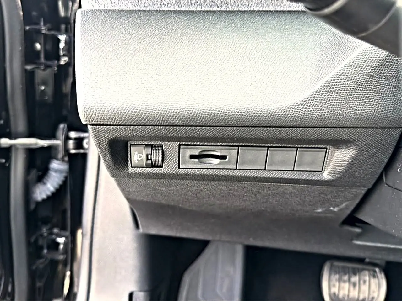 Détail intérieur côté gauche du tableau de bord noir avec commandes d’éclairage sur Peugeot 408 Hybrid 2024.