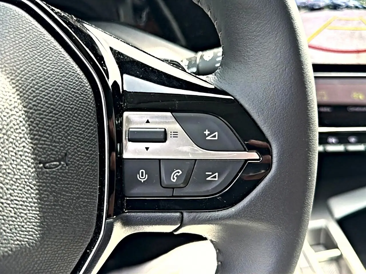 Gros plan sur les commandes vocales et téléphone du volant cuir côté gauche d’une Peugeot 408 Hybrid 2024 noire.
