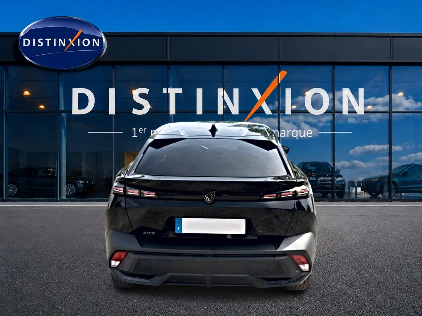 Vue arrière d'une Peugeot 408 Hybrid 136 allure noire, avec feux LED et lunette arrière surteintée, devant une vitrine Distinxion.