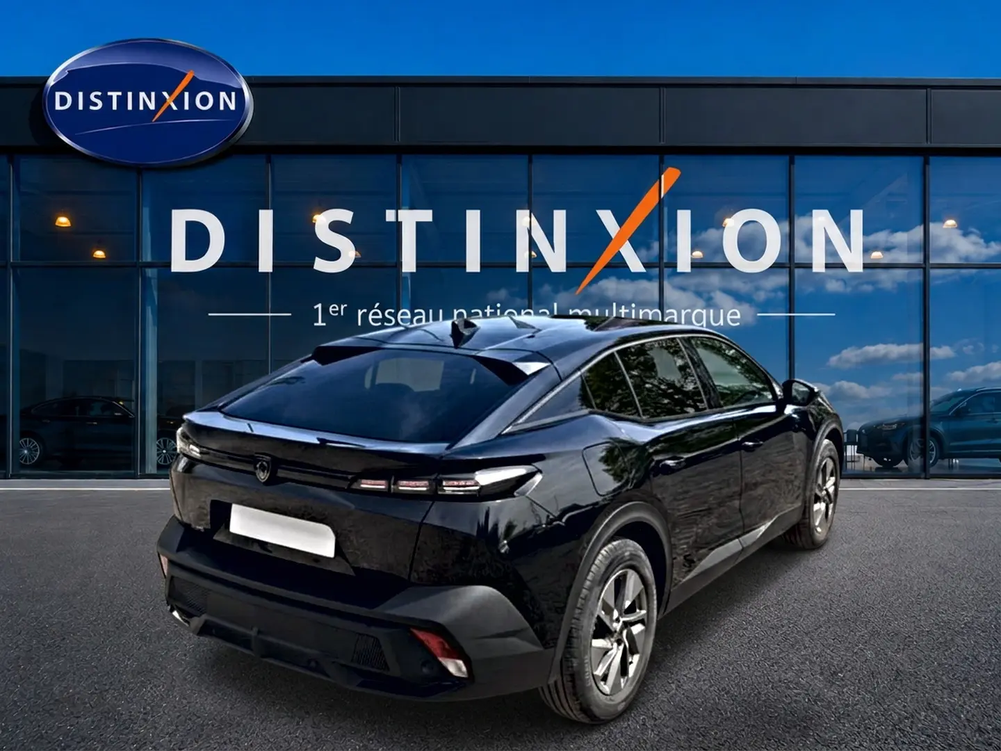 Vue 3/4 arrière droite d'une Peugeot 408 Hybrid 136 allure e-dcs6 noire, avec vitres surteintées et jantes alu devant un showroom Distinxion.