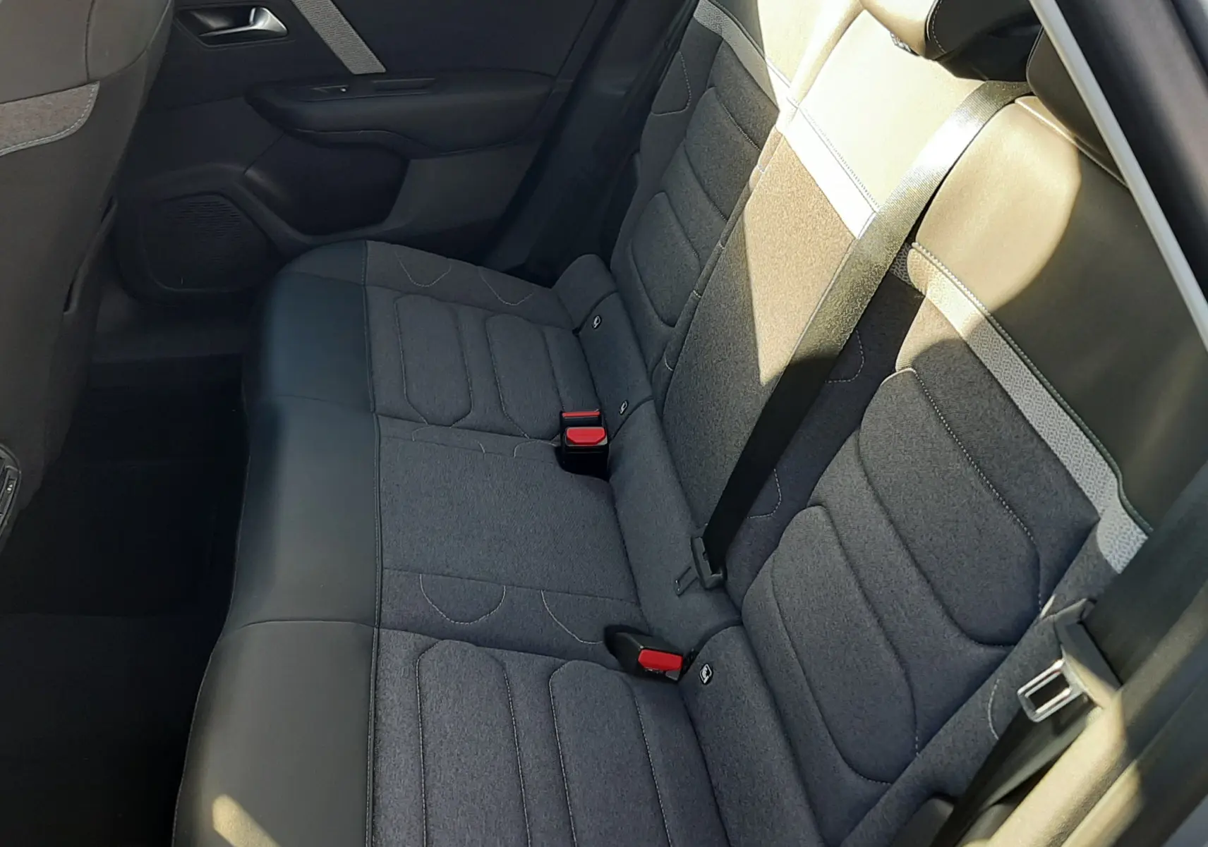 Vue intérieure côté droit des sièges arrière gris tissu et cuir du Citroën C4 2023, avec ceintures de sécurité visibles.