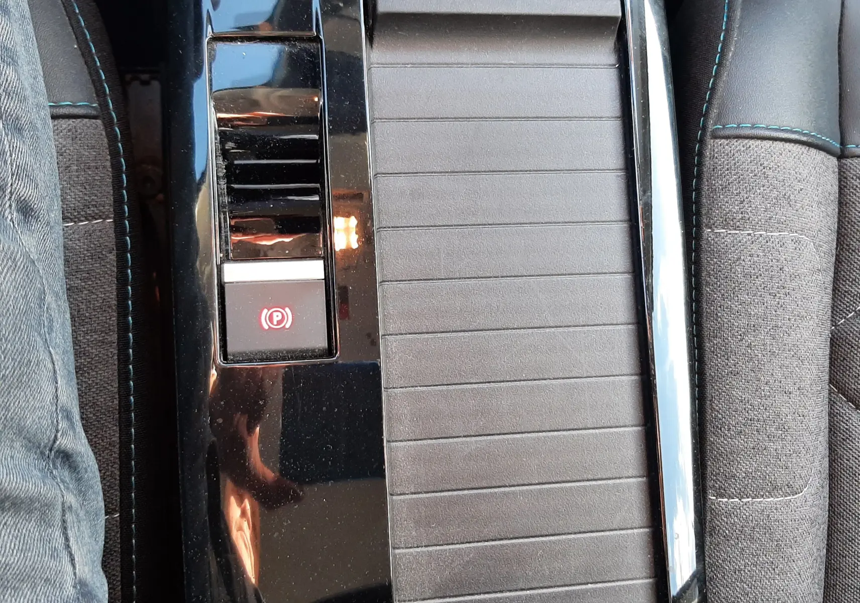 Vue rapprochée de la console centrale noire avec frein à main électronique dans l'habitacle gris du Citroën C4 2023.
