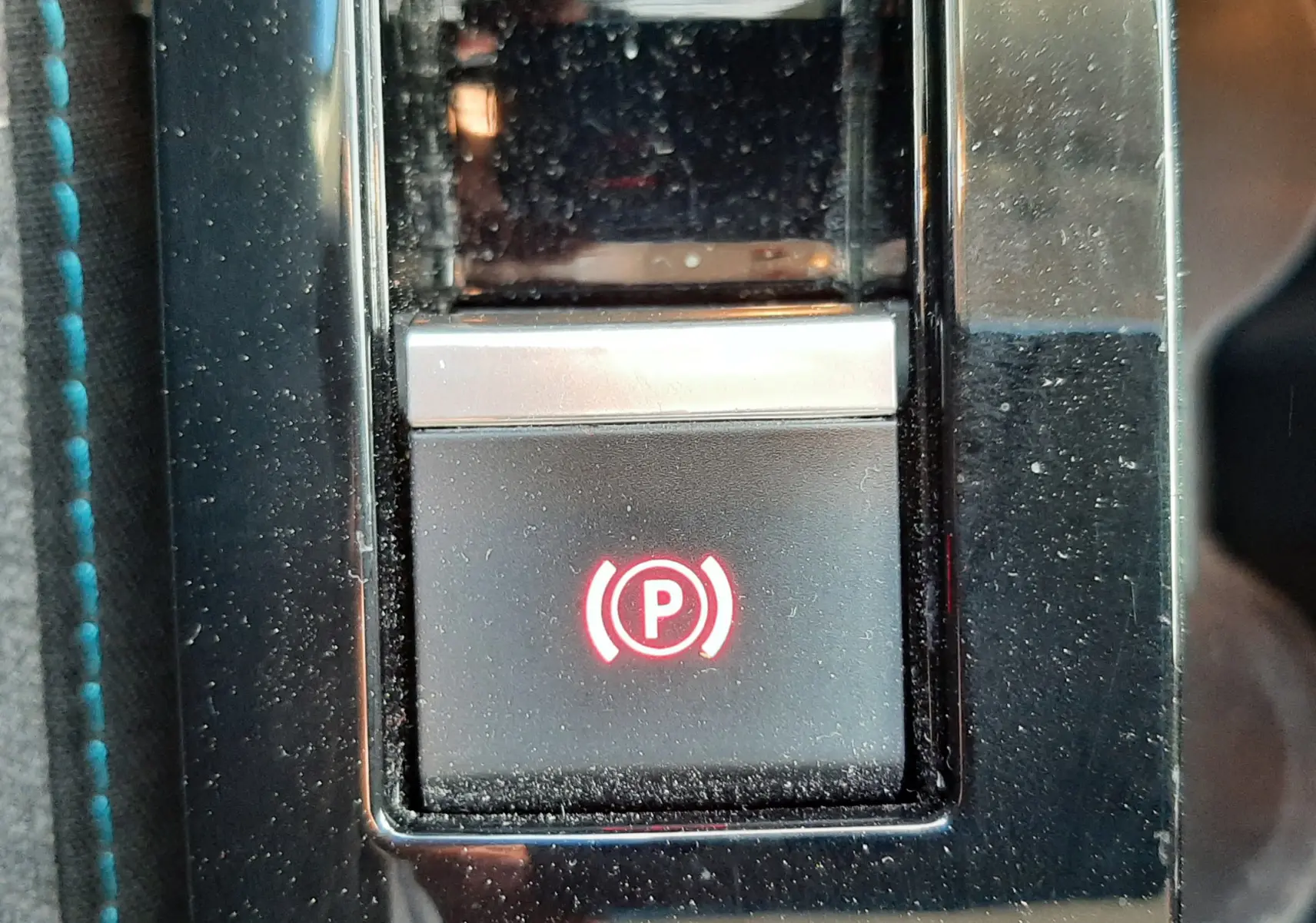 Gros plan sur le bouton de frein à main électronique illuminé en rouge dans l'habitacle gris d'une Citroën C4 2023.