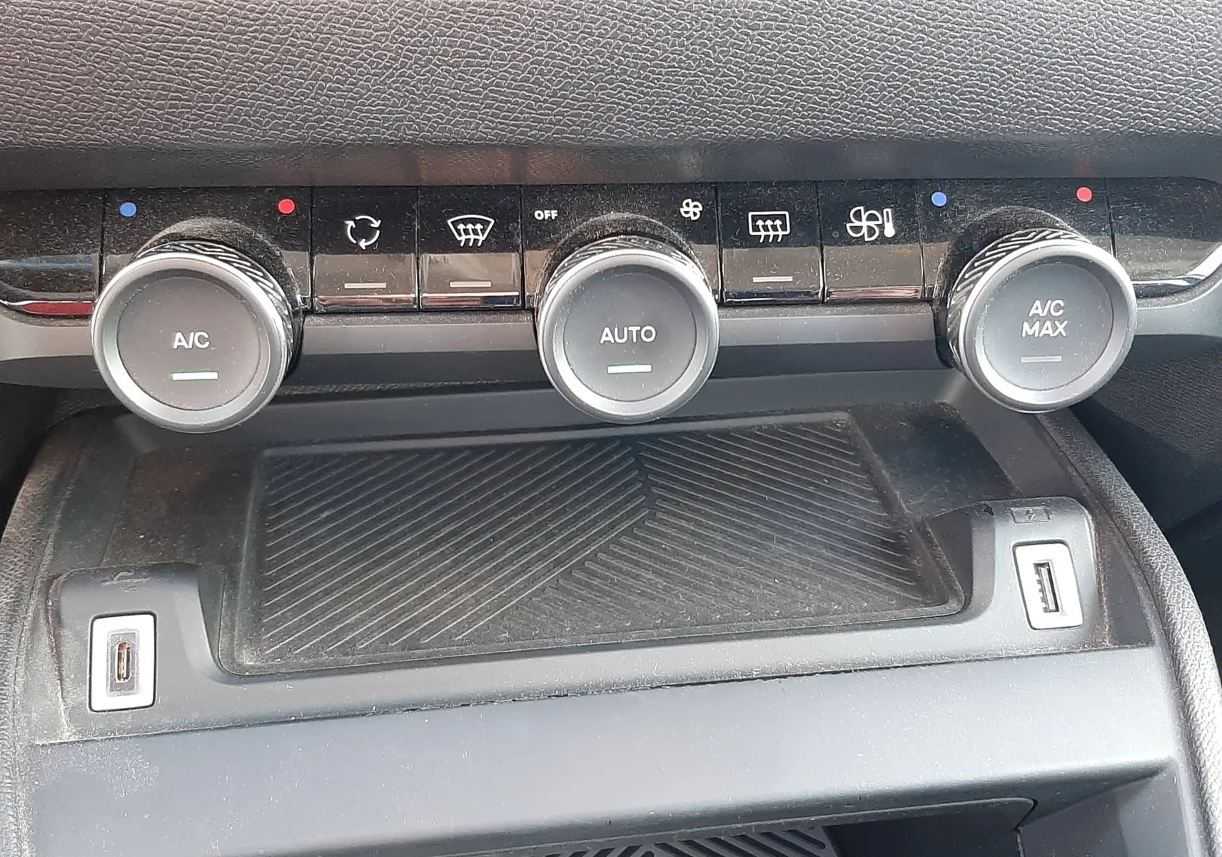Détail de la console centrale grise du Citroën C4 2023 montrant les commandes de climatisation avec trois boutons rotatifs et deux ports USB.
