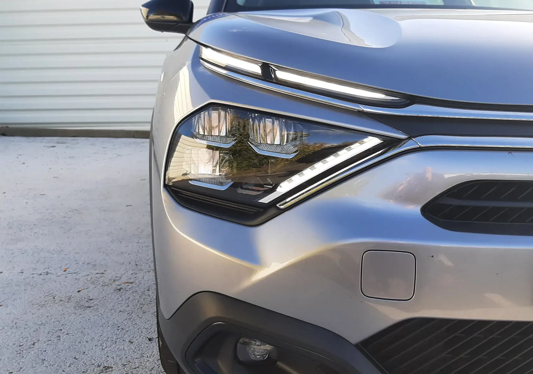 Gros plan sur l'avant droit gris d'une Citroën C4 2023 avec phares LED et calandre distinctive.