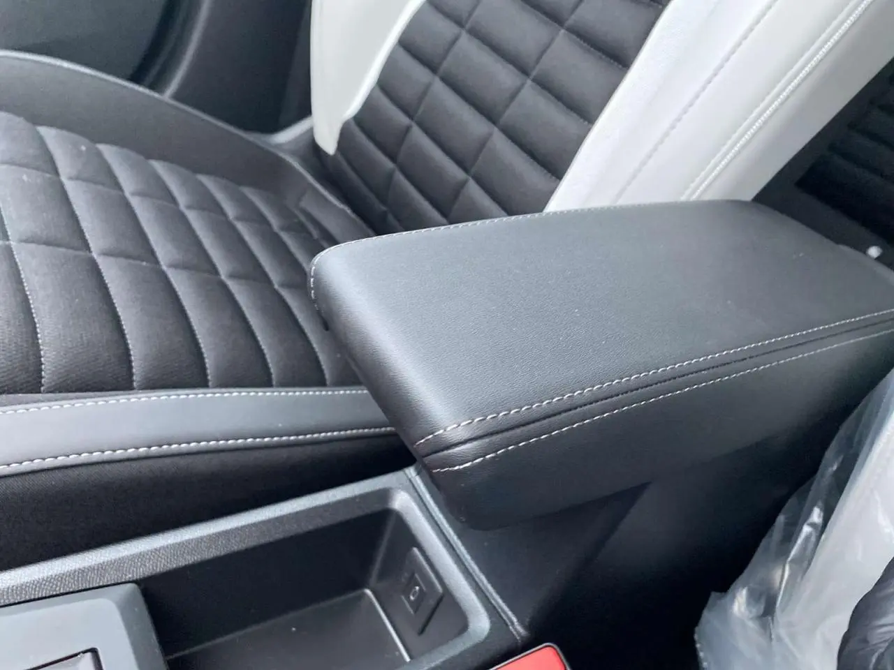 Gros plan sur l'accoudoir central noir et la sellerie bicolore noire et blanche du Citroën C3 Aircross 2025.