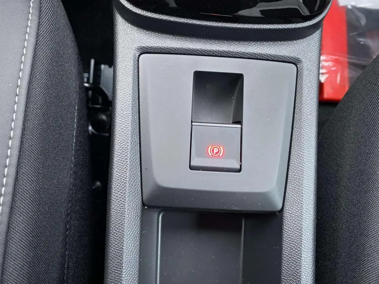 Gros plan sur la commande du frein de stationnement électrique dans la console centrale d'une Citroën C3 Aircross 2025.