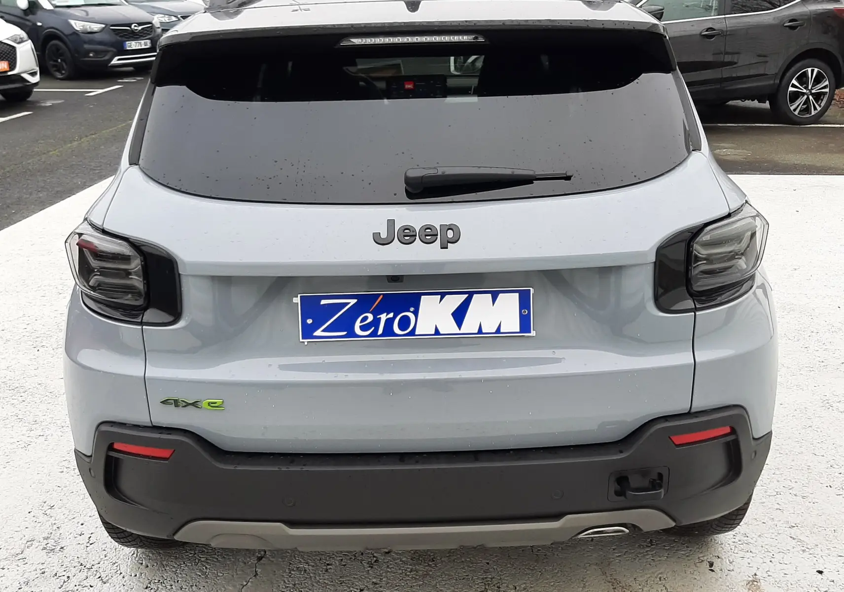Vue arrière d'un Jeep Avenger gris Storm avec toit noir, badge 4xe vert et feux arrière fumés.