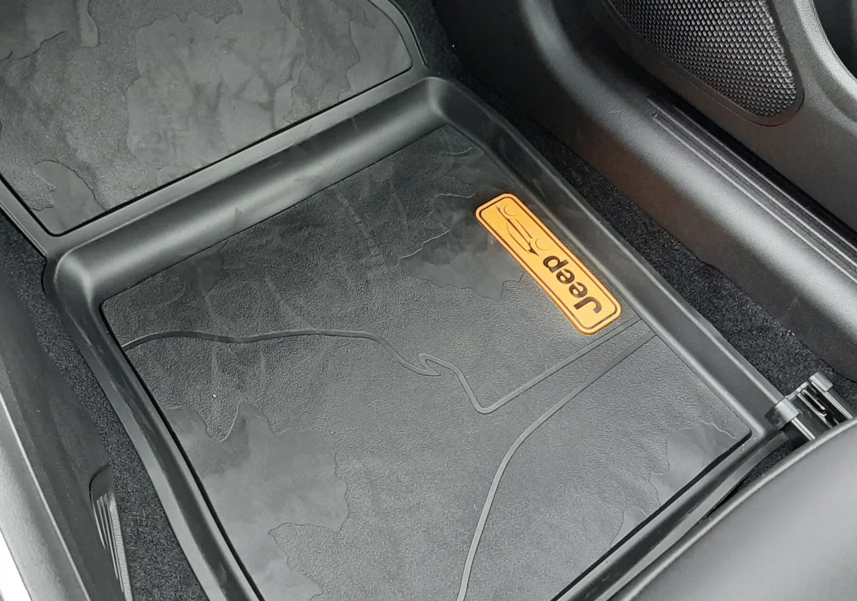 Vue en plongée du tapis de sol noir avec logo Jeep orange à l'avant droit du Jeep Avenger 2025 Storm Grey.