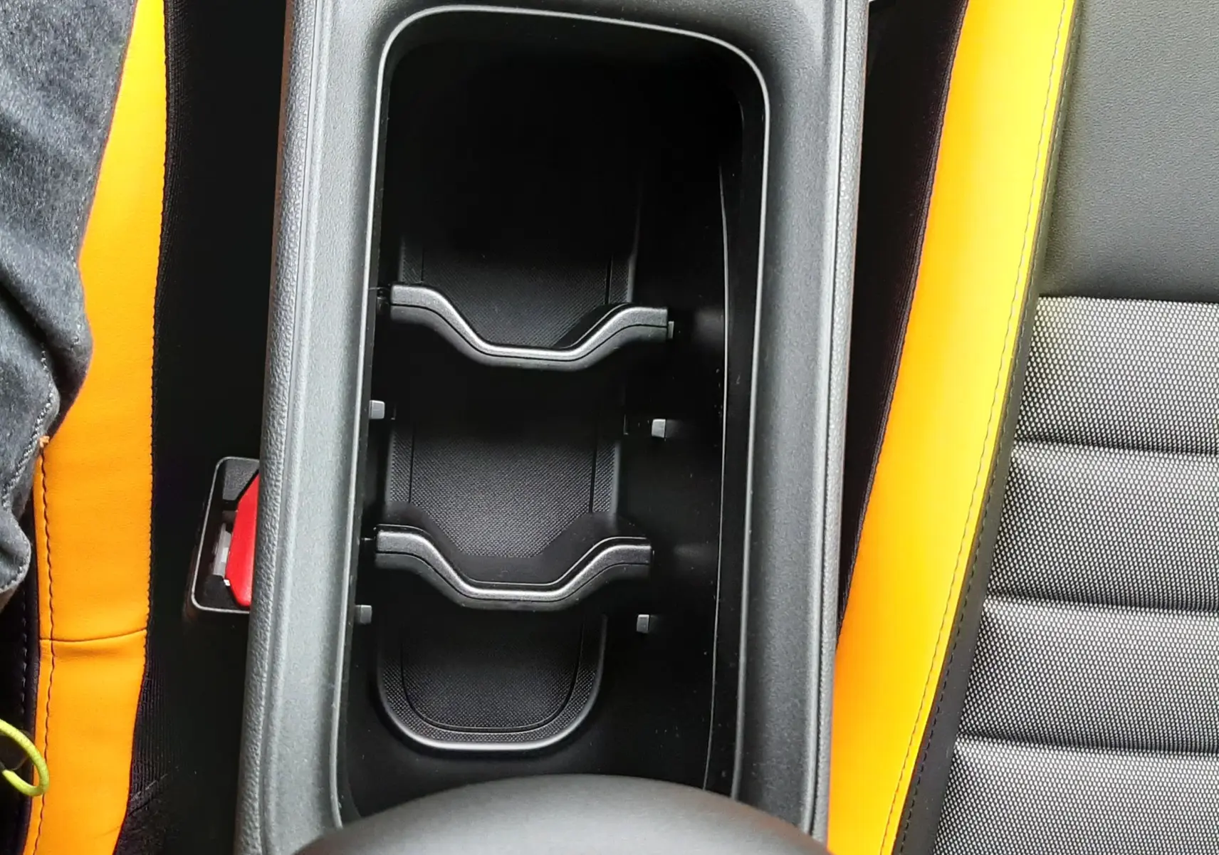 Gros plan intérieur sur le rangement central et les sièges noirs avec surpiqûres jaunes du Jeep Avenger 2025.