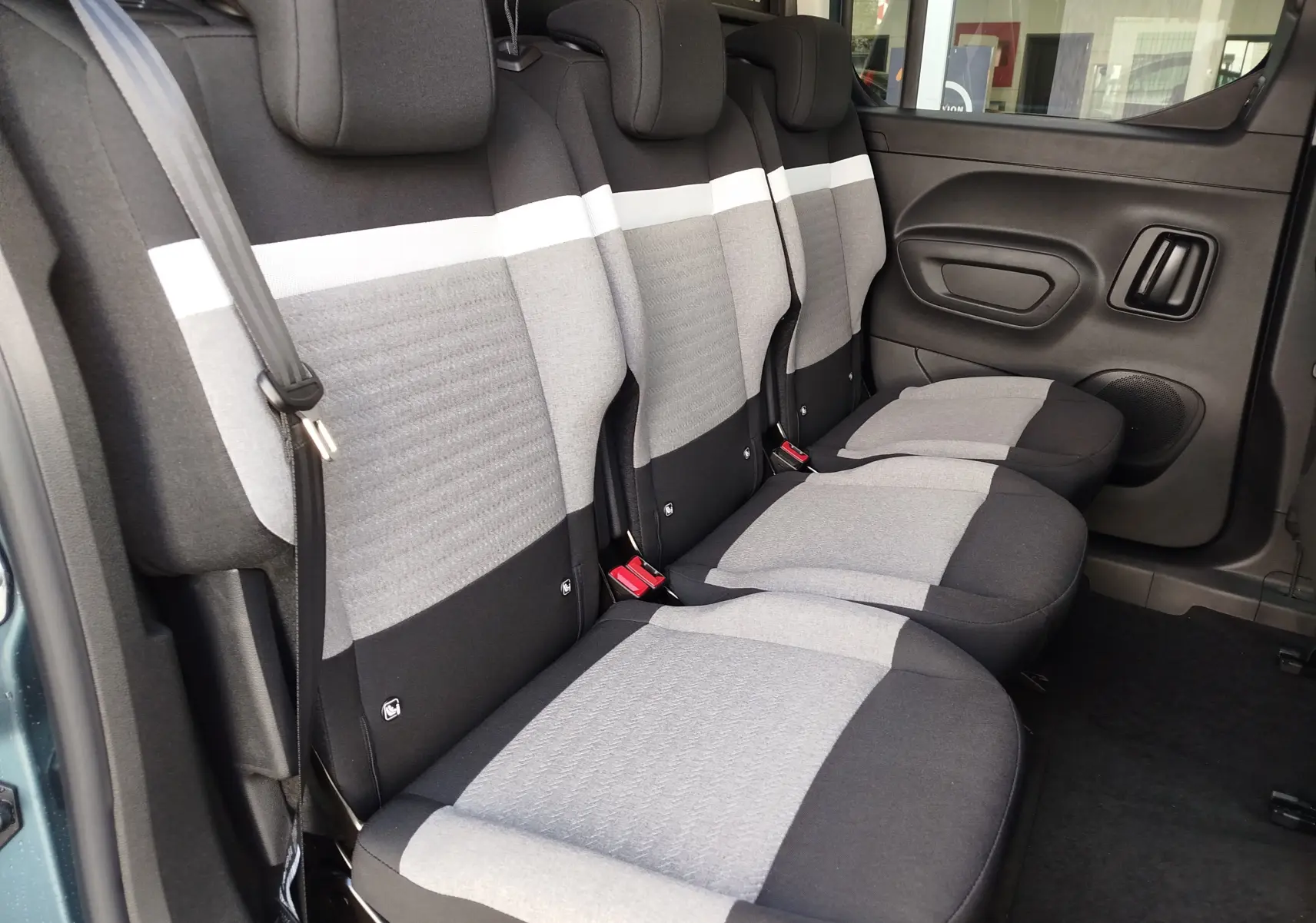 Vue intérieure côté droit des sièges arrière gris clair et foncé du Citroën Berlingo M 2025, avec ceinture de sécurité visible.