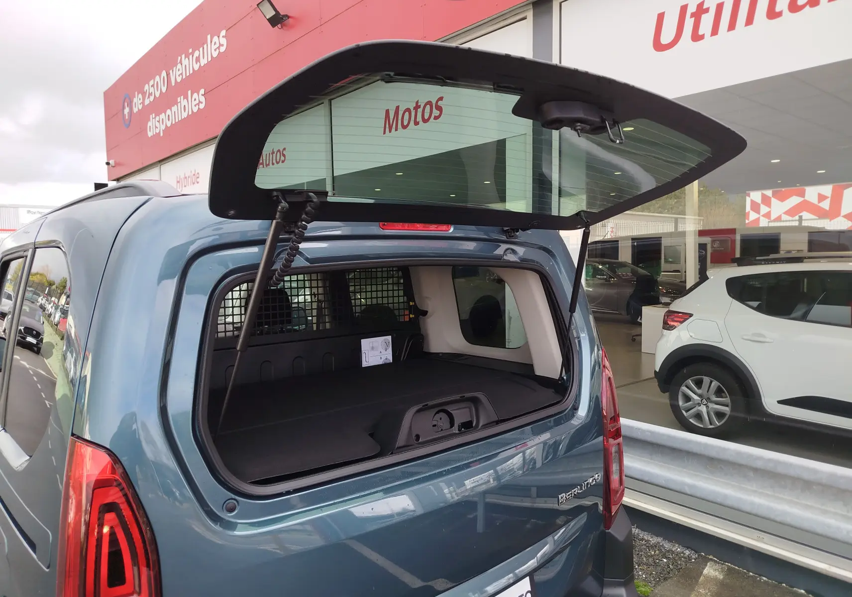 Vue arrière 3/4 du Citroën Berlingo bleu Kiarma 2025 avec hayon ouvert, montrant l'espace de chargement vide.