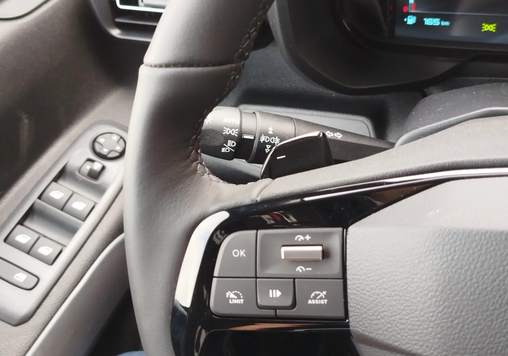 Gros plan sur le volant et les commandes à gauche du tableau de bord d’un Citroën Berlingo 2025, intérieur gris.