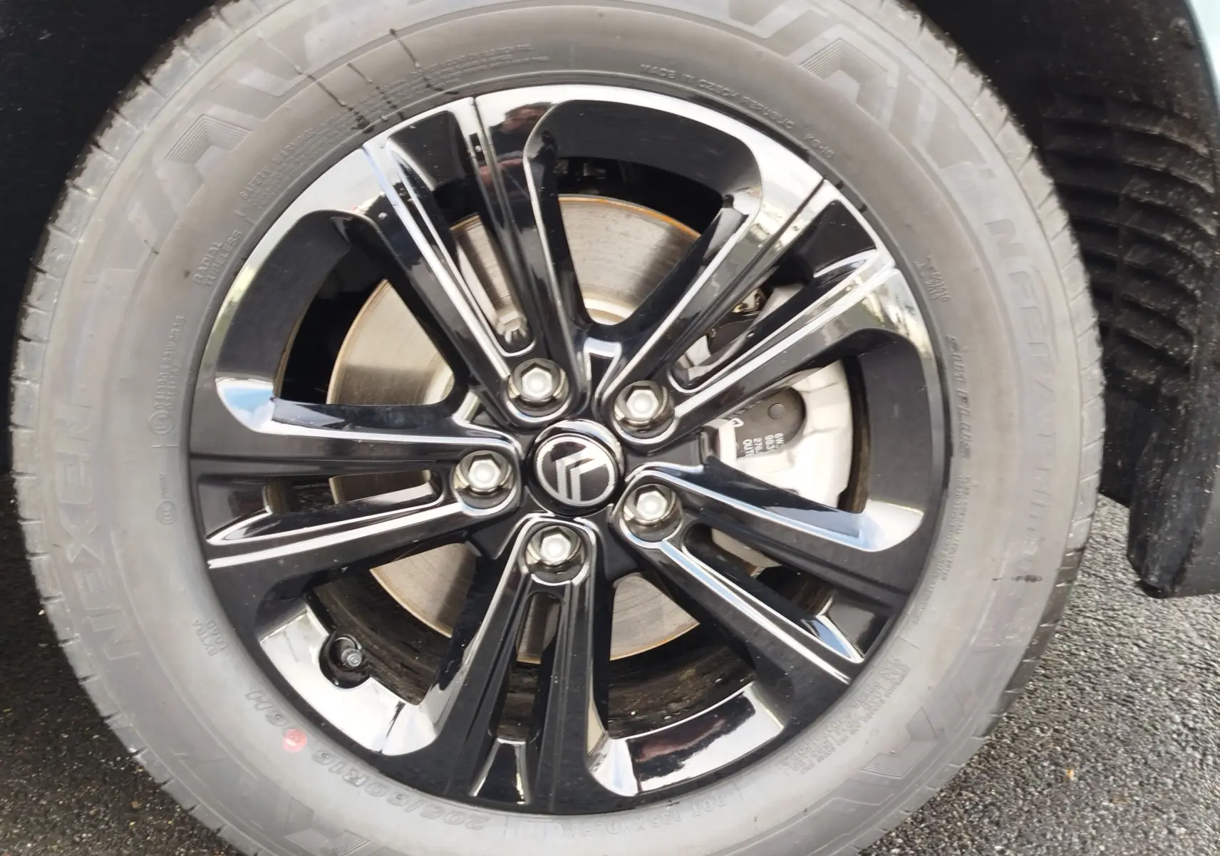 Gros plan sur la jante noire brillante avec logo Citroën au centre, montée sur un pneu Nexen d’un Berlingo bleu Kiarma.