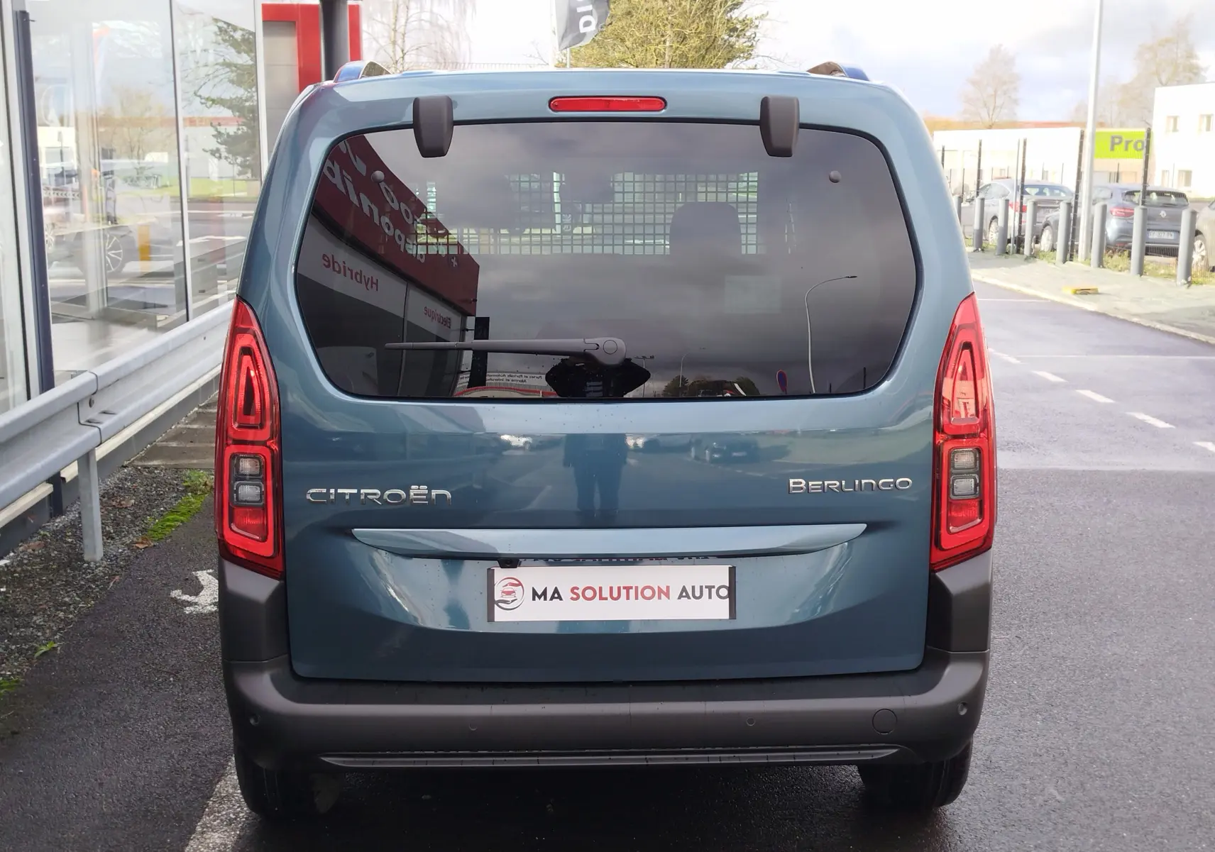 Vue arrière d'un Citroën Berlingo bleu Kiarma 2025 avec vitres teintées et feux arrière verticaux allumés.