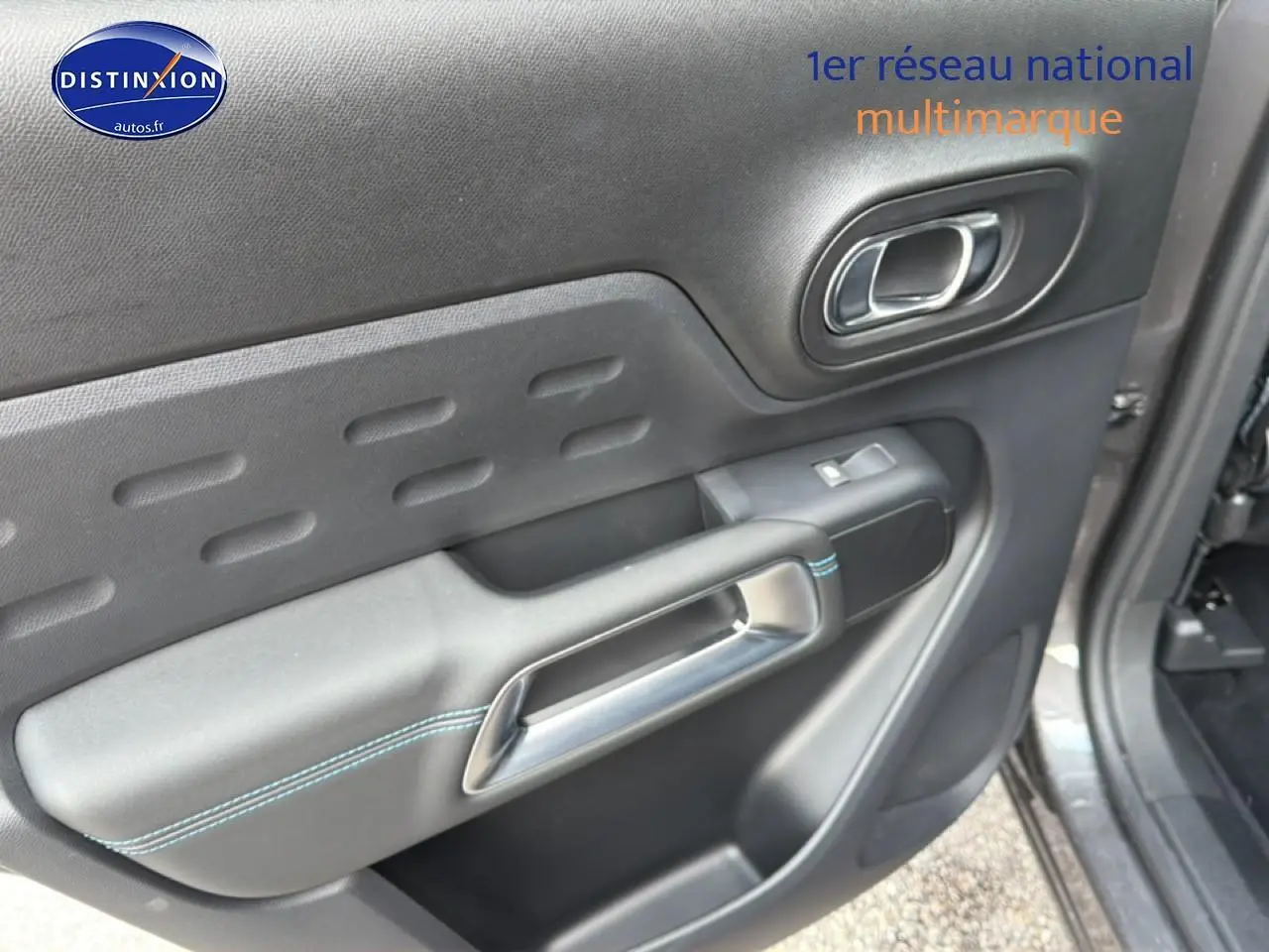 Gros plan sur la porte intérieure côté droit du Citroën C5 Aircross gris platinium avec surpiqûres bleues et poignée argentée.