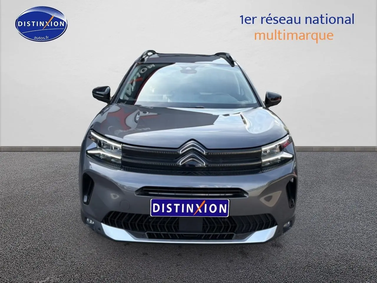 Vue avant d'un Citroën C5 Aircross gris platinium 2025 avec calandre distinctive et barres de toit visibles.