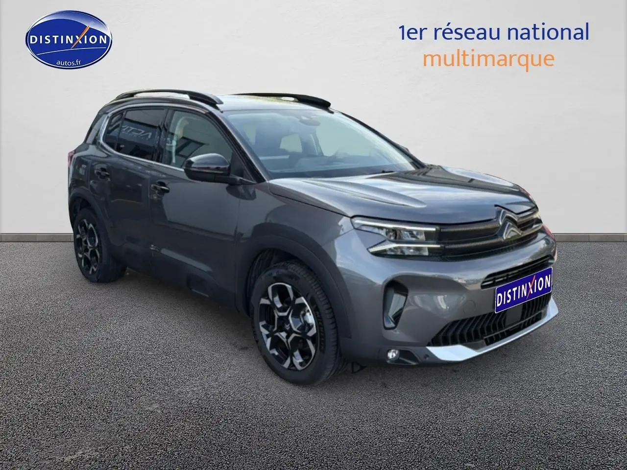Citroën C5 Aircross gris platinium en 3/4 avant droit, avec barres de toit et jantes alu distinctives.