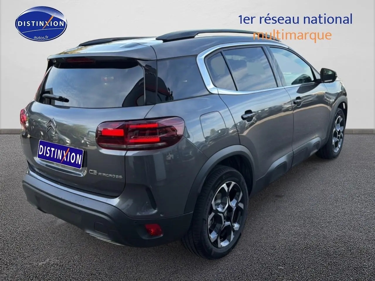 Vue 3/4 arrière droite d'un Citroën C5 Aircross gris platinium avec barres de toit et jantes alu distinctives.