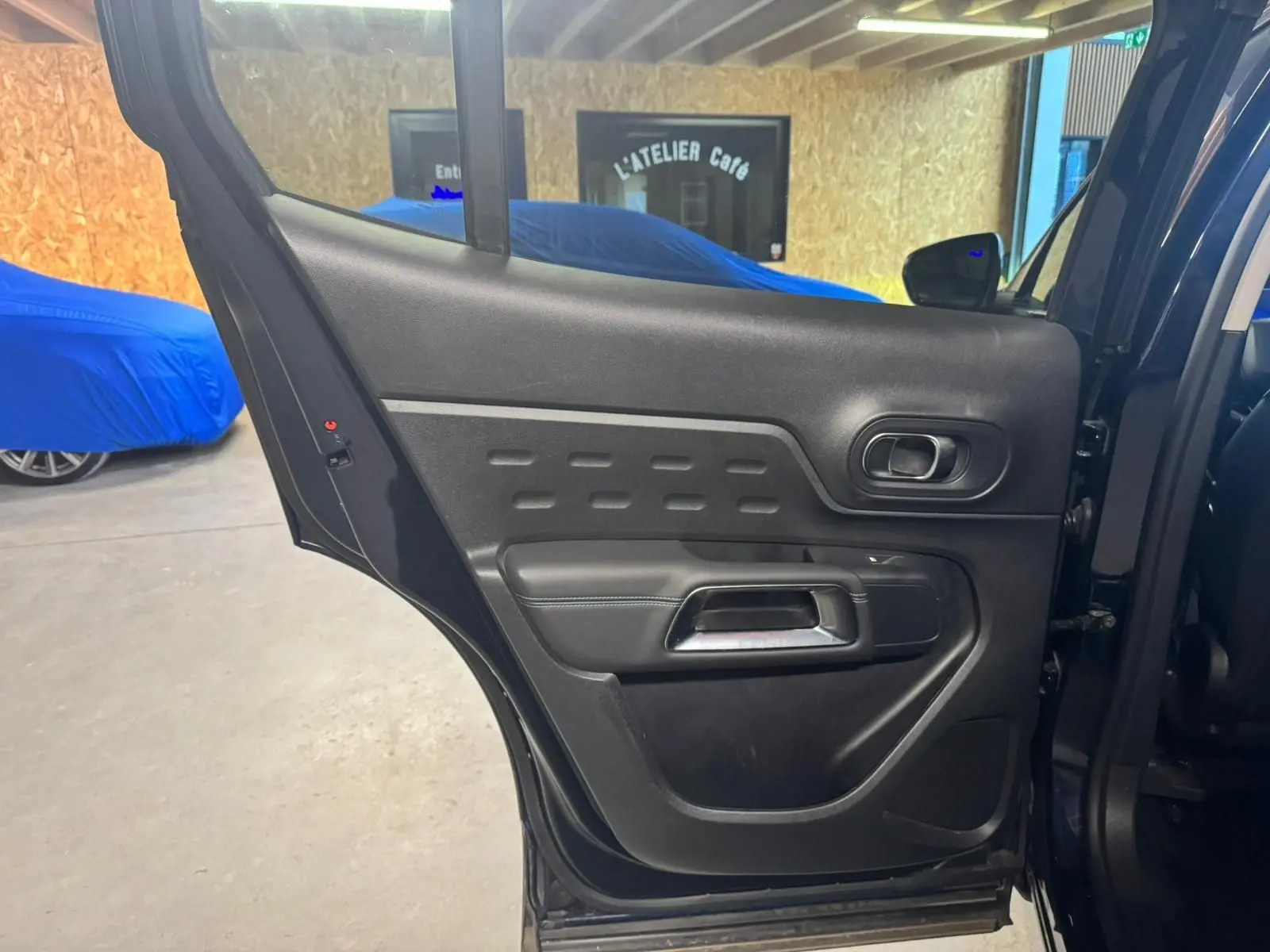 Vue intérieure rapprochée des sièges avant gris foncé du Citroën C5 Aircross 2022 avec accoudoir central et porte-gobelets.