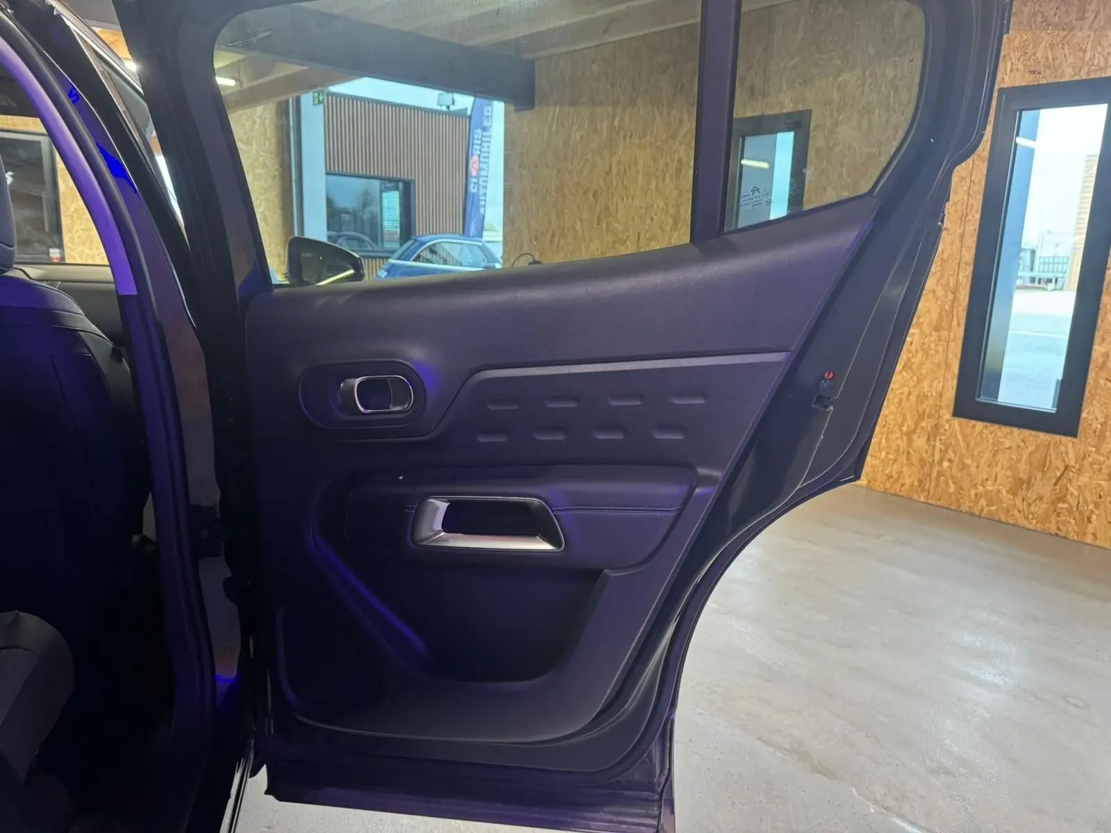 Gros plan sur la porte arrière gauche intérieure du Citroën C5 Aircross bleu, avec poignée argentée et panneau noir texturé.