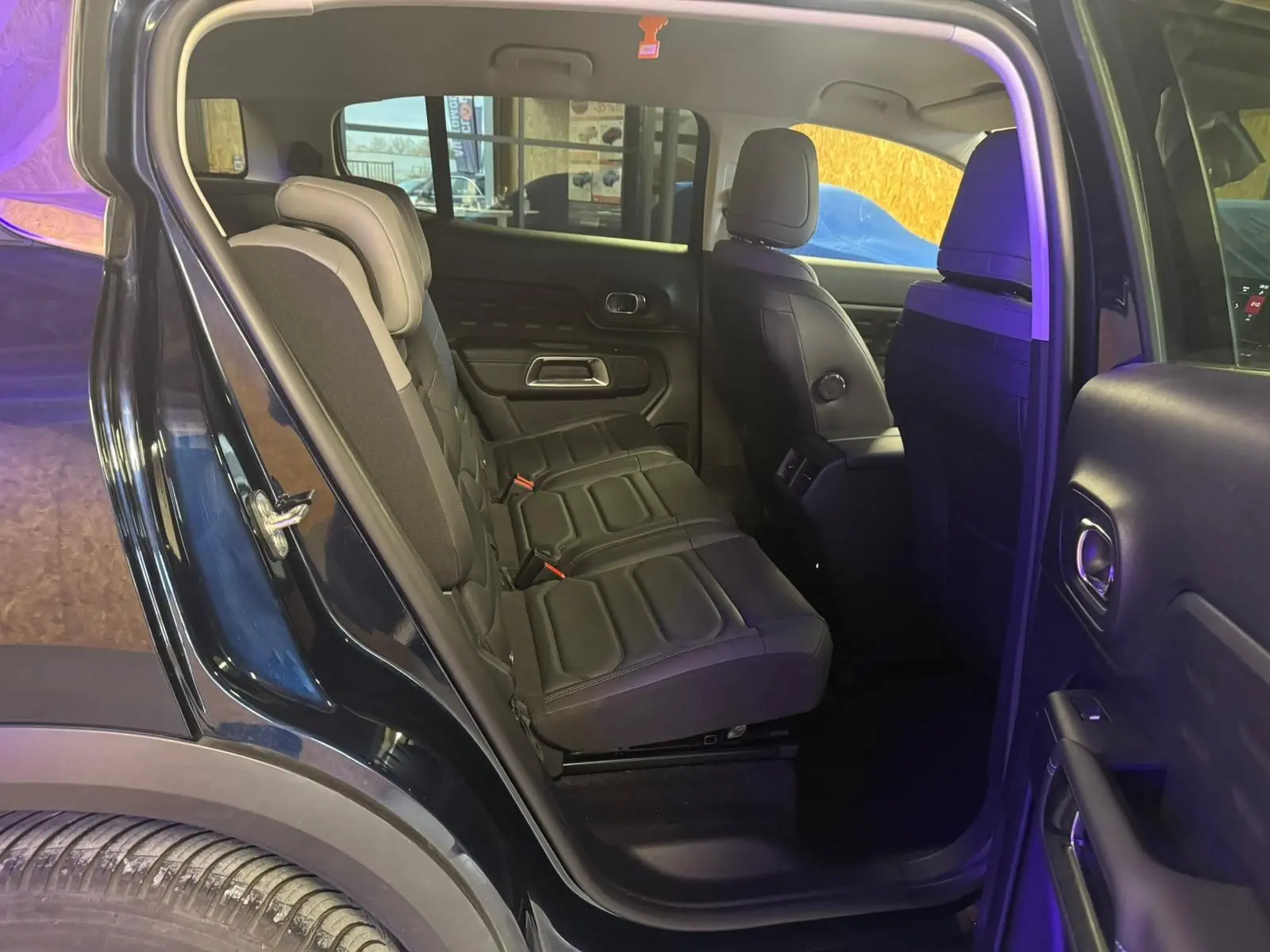 Gros plan sur la poignée intérieure et la commande de vitre côté gauche de la porte avant noire du Citroën C5 Aircross.