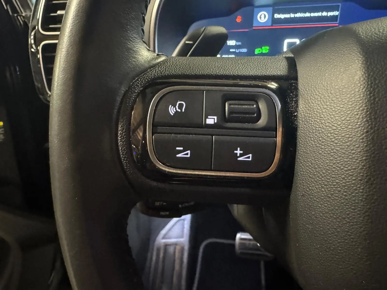 Vue rapprochée du volant en cuir noir du Citroën C5 Aircross avec commandes intégrées et tableau de bord numérique.