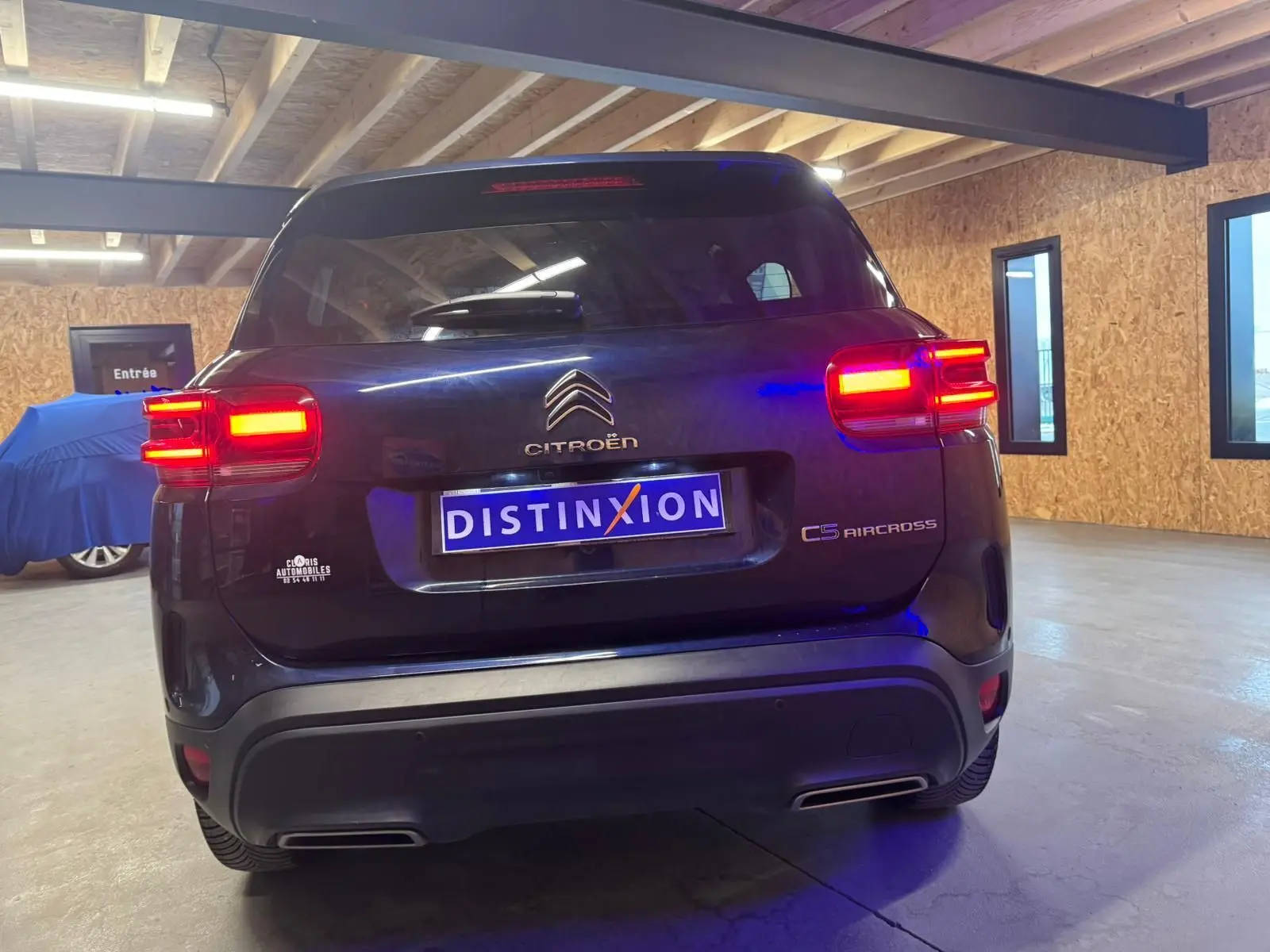Vue 3/4 arrière droite du Citroën C5 Aircross bleu avec feux arrière LED allumés en intérieur.