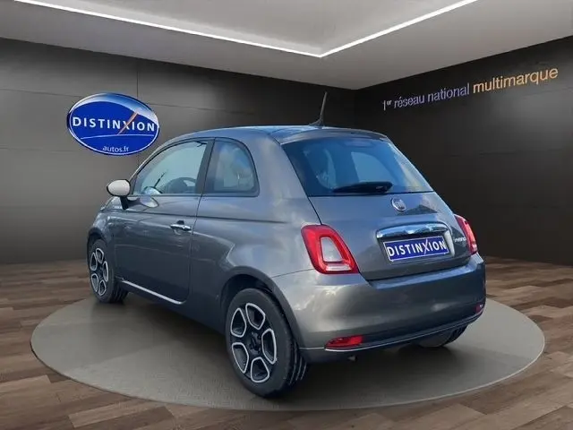 Vue 3/4 arrière droite d'une Fiat 500 gris foncé avec jantes distinctives, dans un showroom intérieur.