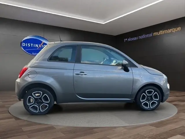 Profil droit d'une FIAT 500 gris foncé 2022, compacte avec jantes alliage distinctives, en intérieur showroom.