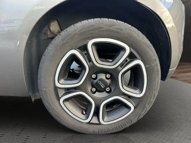 Gros plan sur la roue avant droite d'une FIAT 500 gris foncé, mettant en valeur la jante au design moderne.