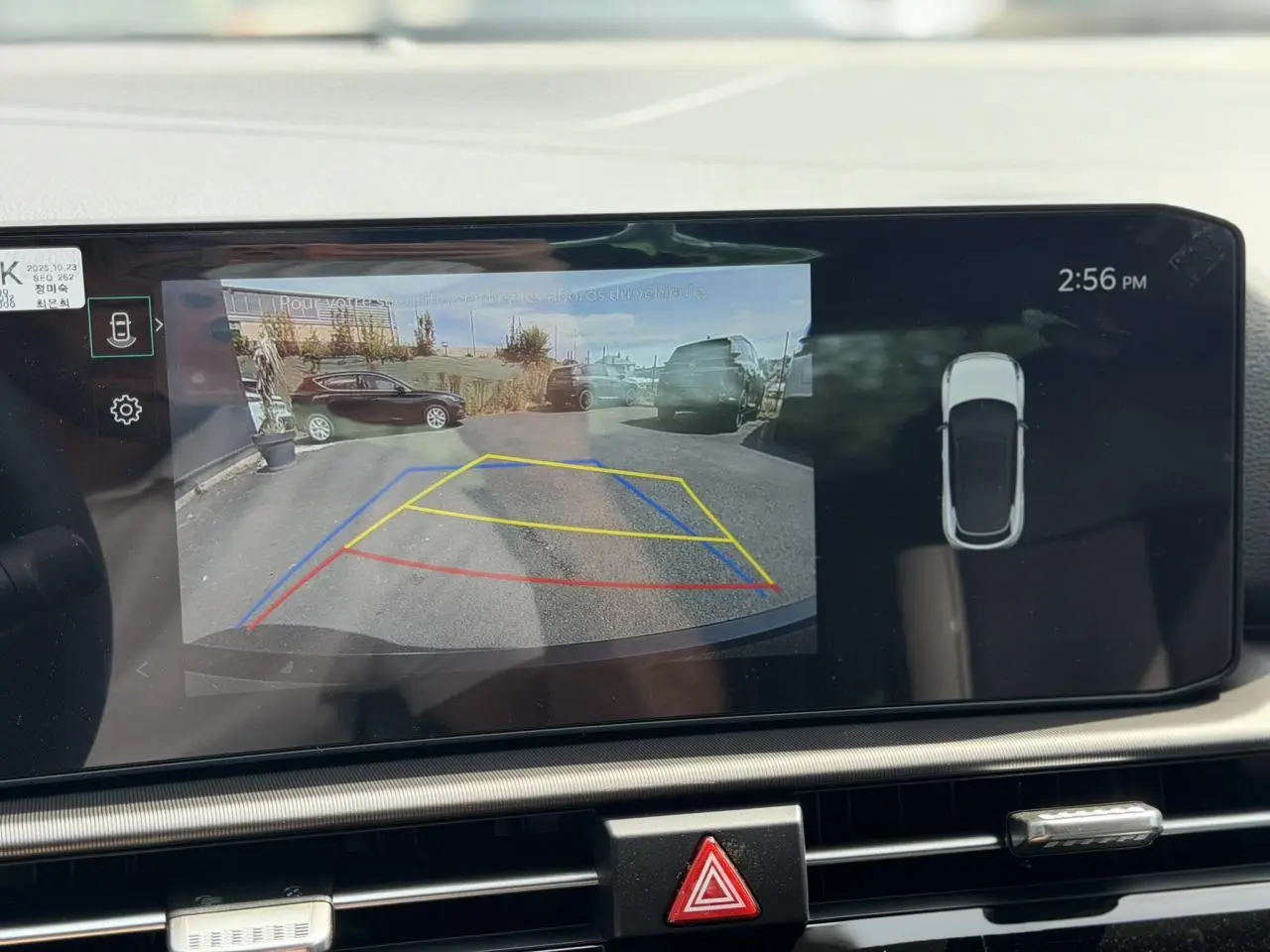 Écran tactile du Kia Sportage blanc montrant la caméra de recul avec lignes de guidage dynamiques.