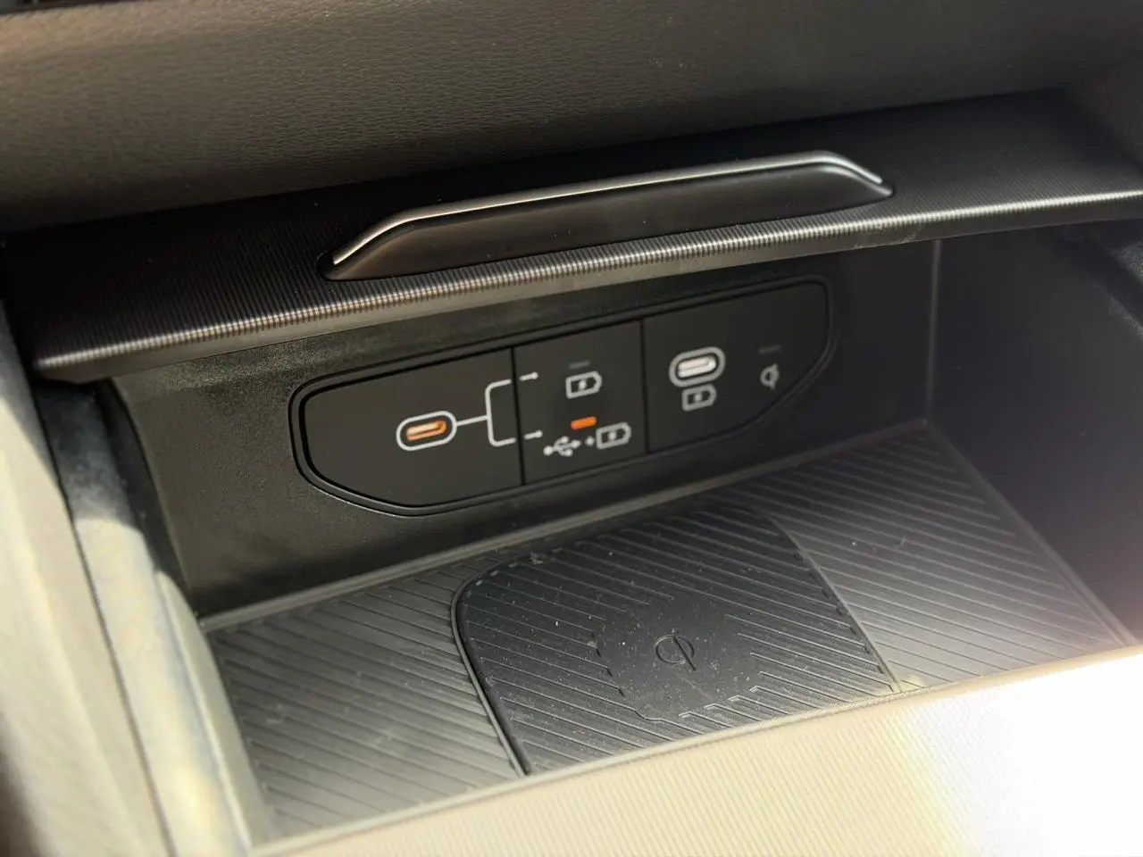 Gros plan sur la console centrale noire avec ports USB-C et zone de recharge sans fil du Kia Sportage blanc 2026.