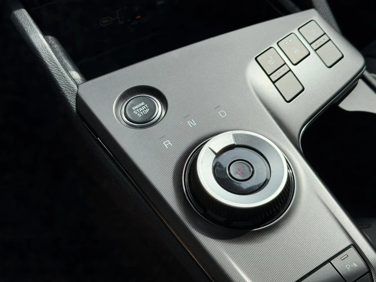 Gros plan sur la console centrale grise du Kia Sportage 2026 avec bouton start/stop et molette de sélection de vitesse.