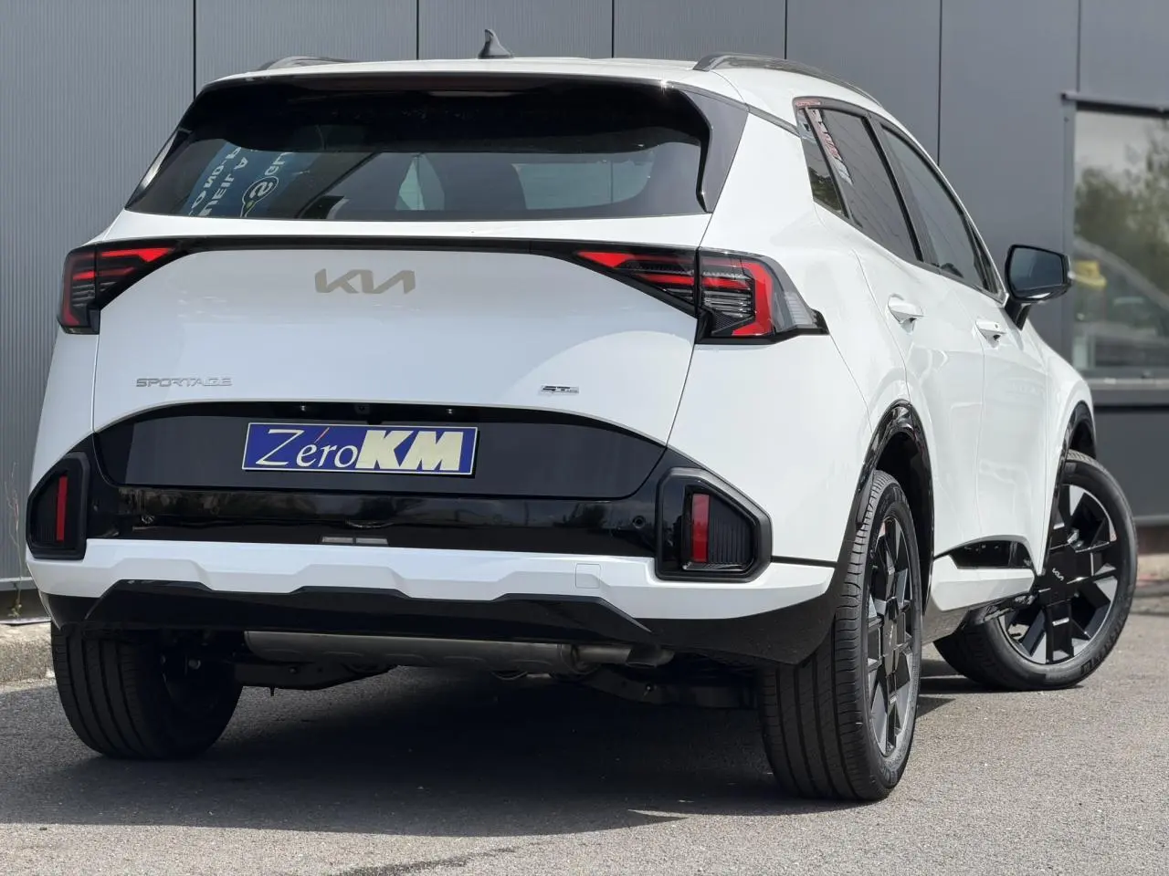 Vue 3/4 arrière droite du KIA Sportage blanc 2026 avec feux arrière LED et jantes alliage noires.