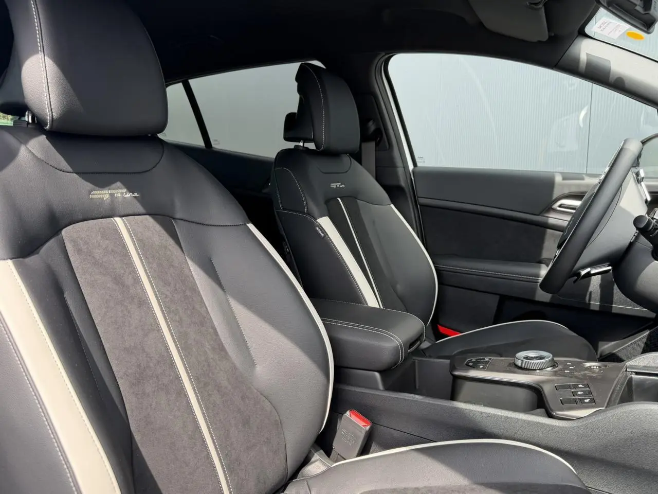 Vue intérieure côté conducteur du Kia Sportage 2026 GT-line, sièges bi-ton noir et gris avec surpiqûres blanches.