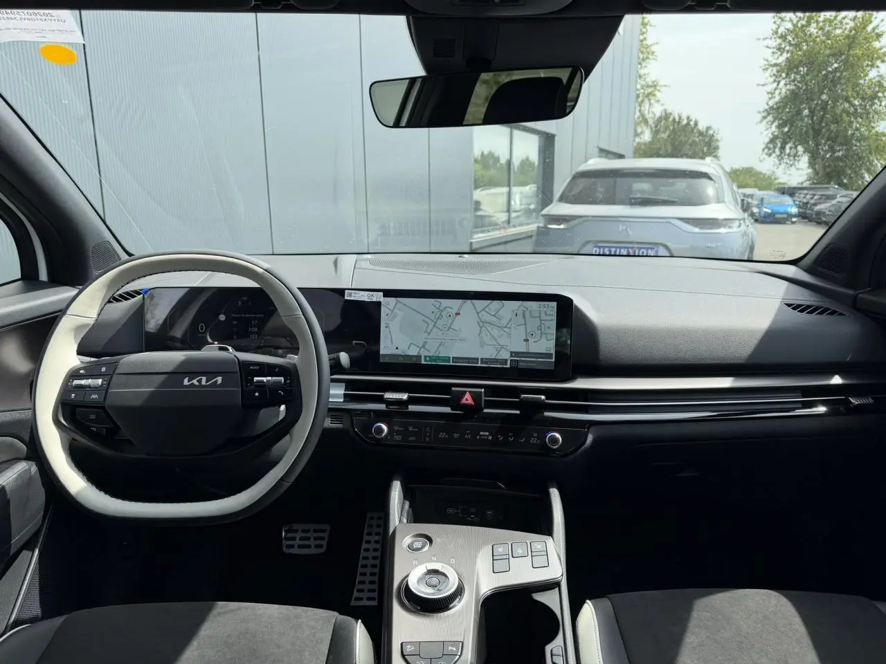 Vue intérieure avant du Kia Sportage 2026, tableau de bord noir avec écran tactile large et volant bi-ton clair et noir.