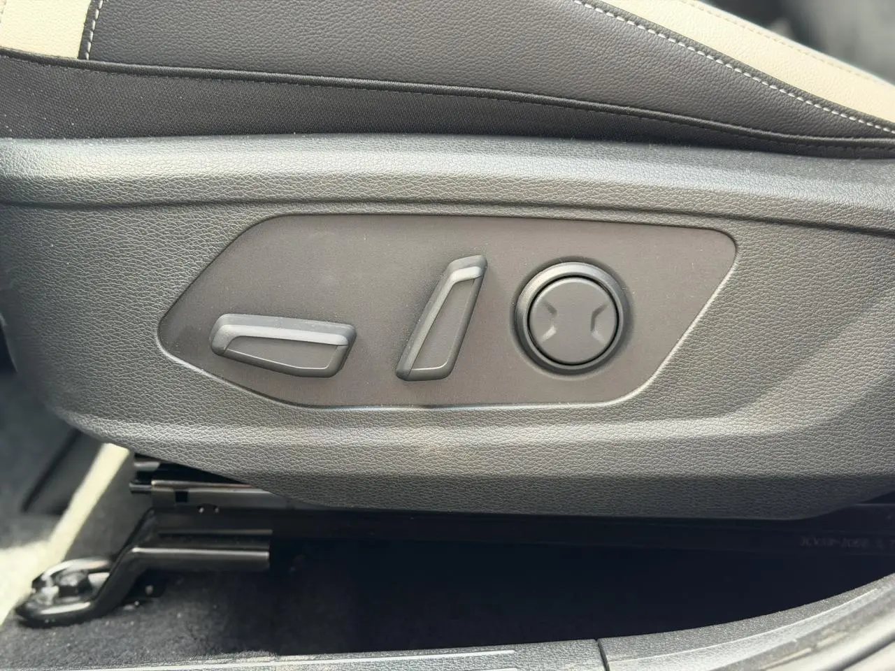 Gros plan sur les commandes électriques de réglage du siège avant côté conducteur du Kia Sportage blanc 2026.
