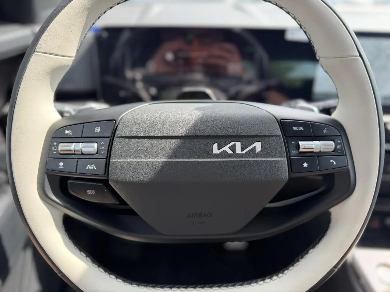 Volant bi-ton noir et beige du Kia Sportage 2026, avec commandes intégrées et logo Kia central visible.