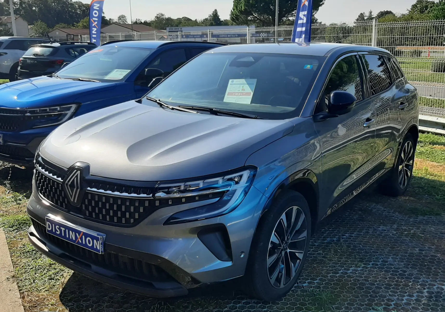 Renault Austral E-Tech Full Hybrid gris schiste, vue 3/4 avant droit, calandre distinctive et jantes alliage bicolores.
