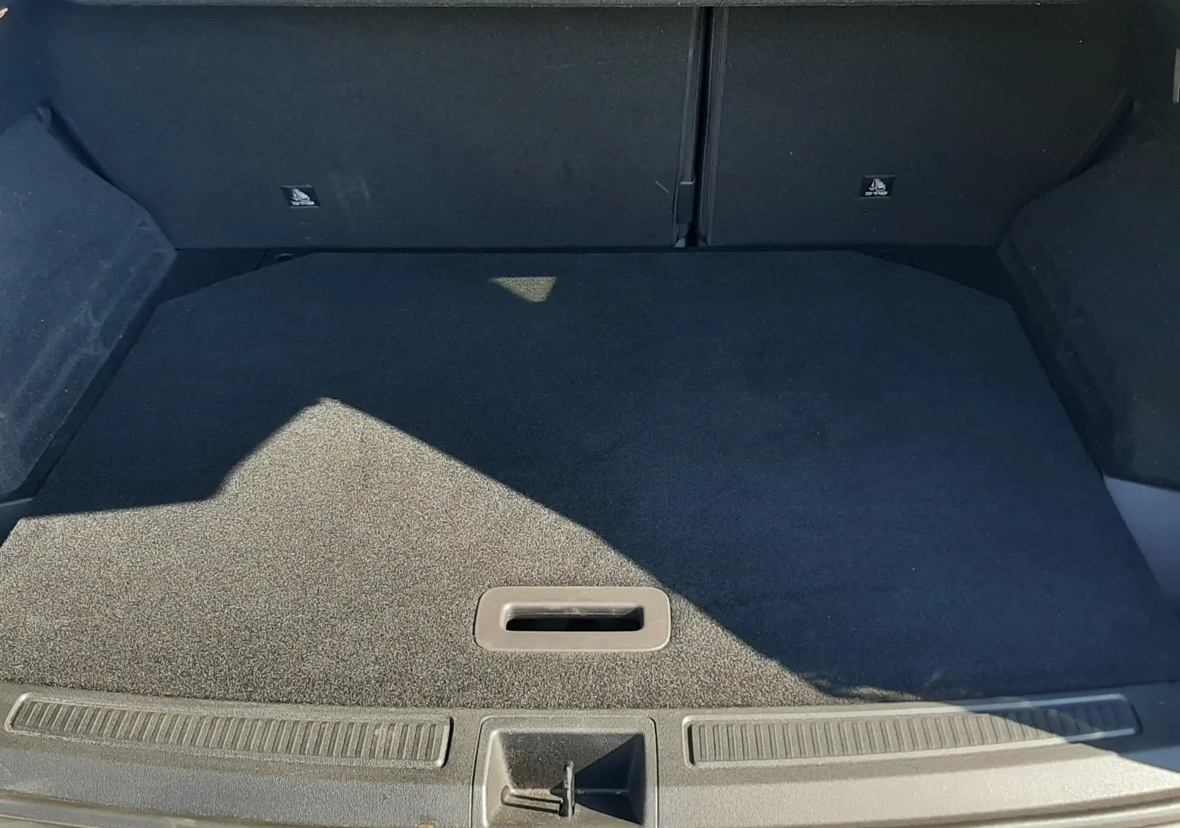 Coffre ouvert du Renault Austral E-Tech gris schiste, vue plongeante sur le tapis de coffre et le seuil de chargement.