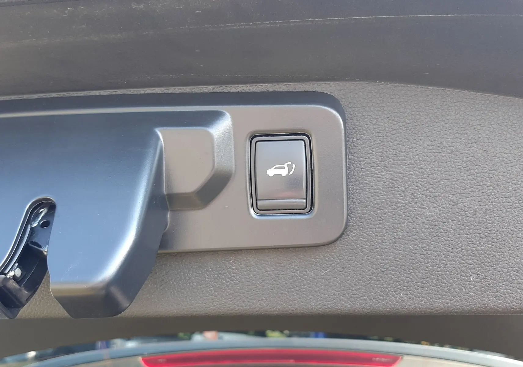 Gros plan sur le bouton d'ouverture électrique du hayon, intérieur noir du Renault Austral gris schiste 2025.