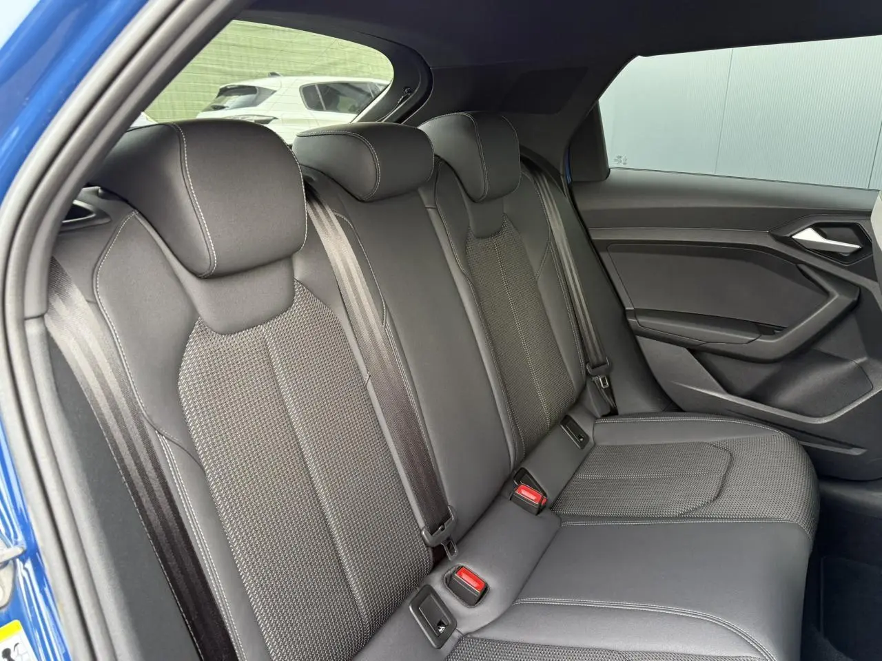Vue côté droit des sièges arrière noirs en cuir et tissu de l'Audi A1 Sportback Bleu Ascari 2023 avec porte ouverte.